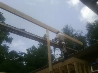 Carpenter setting a ridge beam over a new addition frame — Ice Dam Removal by Roofing Brothers in Bowlus