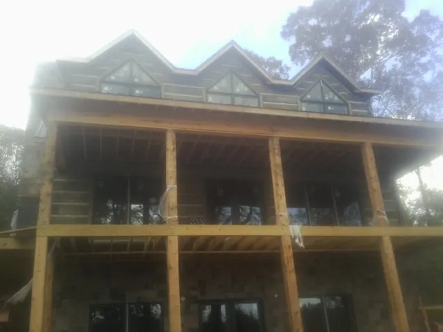Dormers and porch framing on a large log home under construction — Roof Coating work by our crew in Bowlus