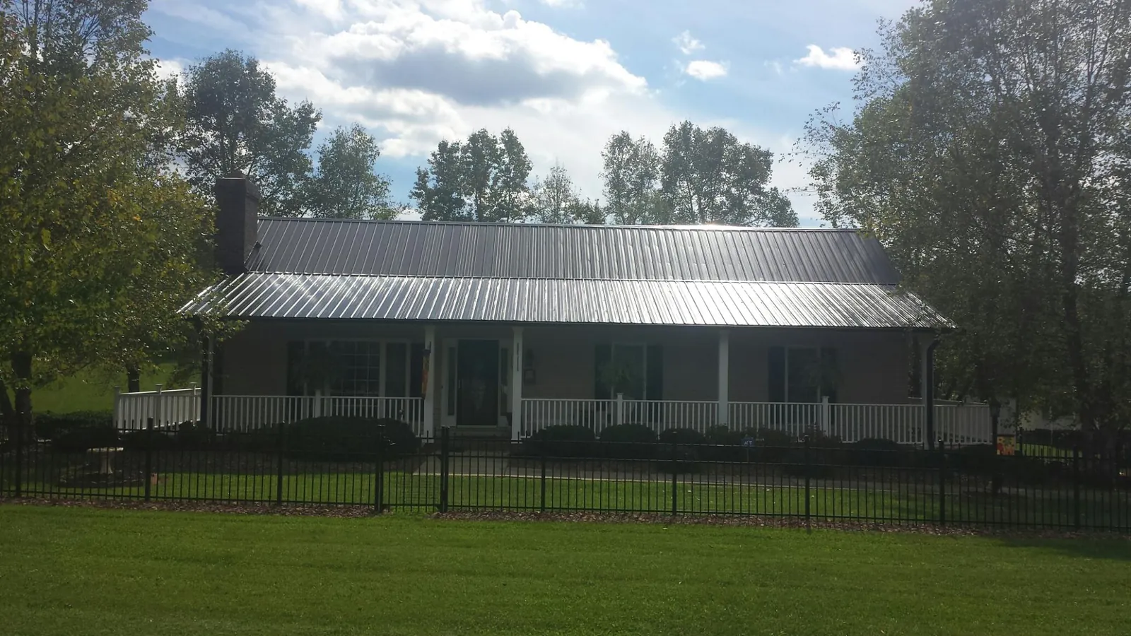 Gray metal roof on a brick ranch with a full width front porch — Gutter Guard Installation work by our crew in Bowlus