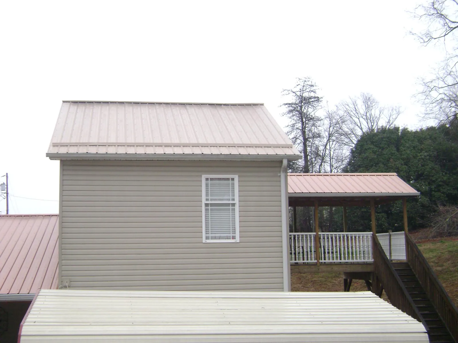Tan metal roofs on a two story addition and attached porch, from a Roof Replacement job in Bowlus