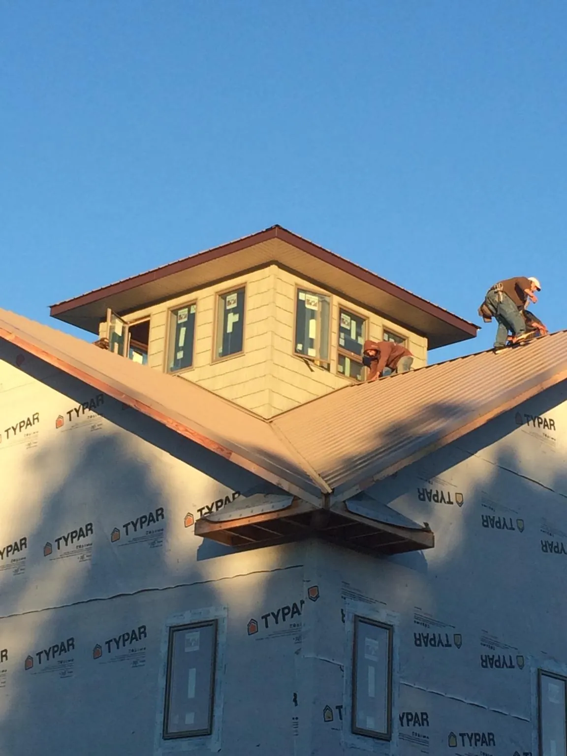 Roofers working around a rooftop cupola on a new metal roof at sunset — Roof Waterproofing in Bowlus by Roofing Brothers